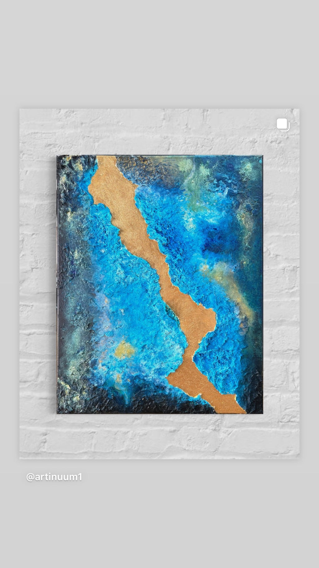 Abstract art piece with blue and gold colors on a textured white wall.