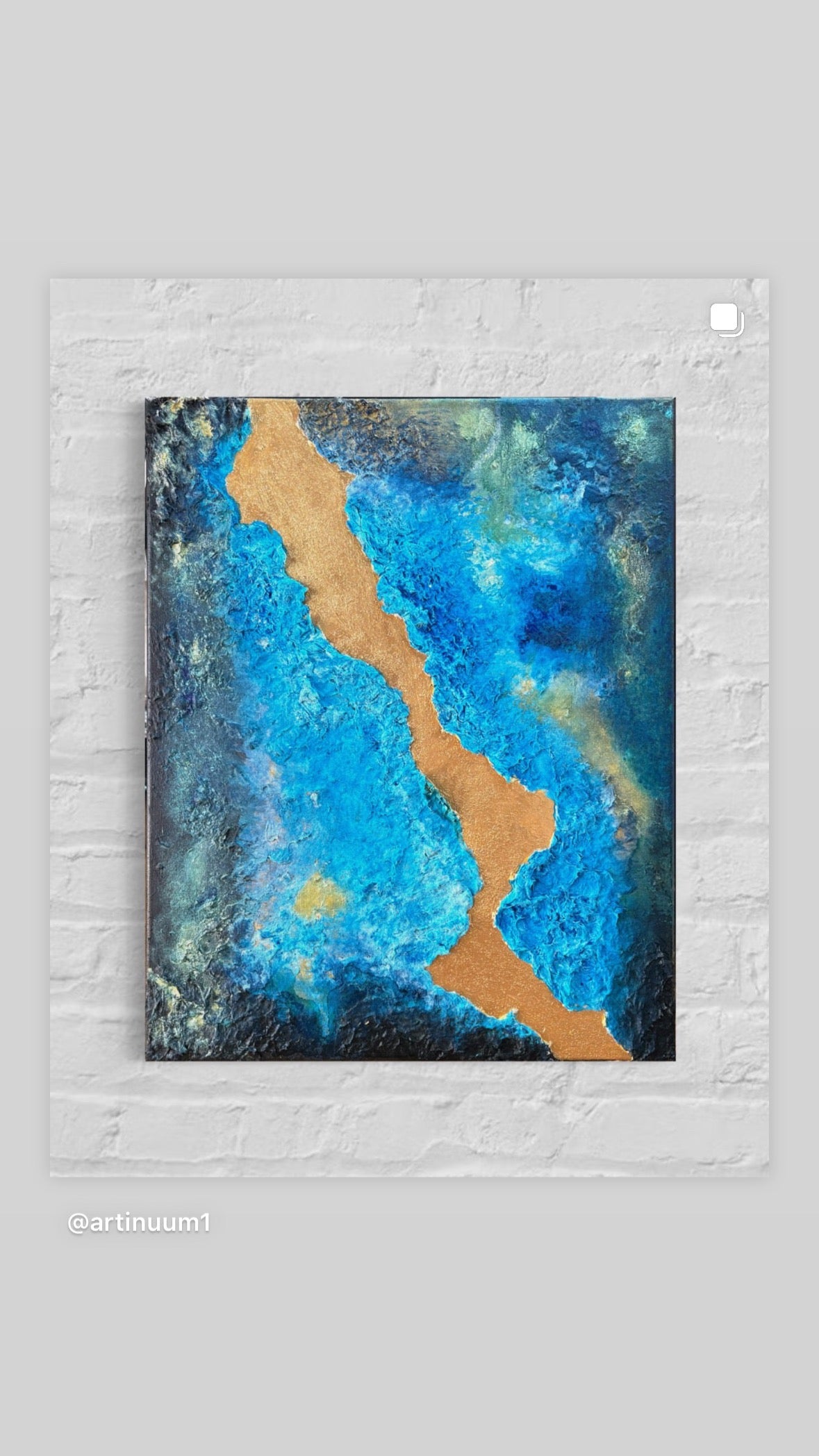 Abstract art piece with blue and gold colors on a textured white wall.