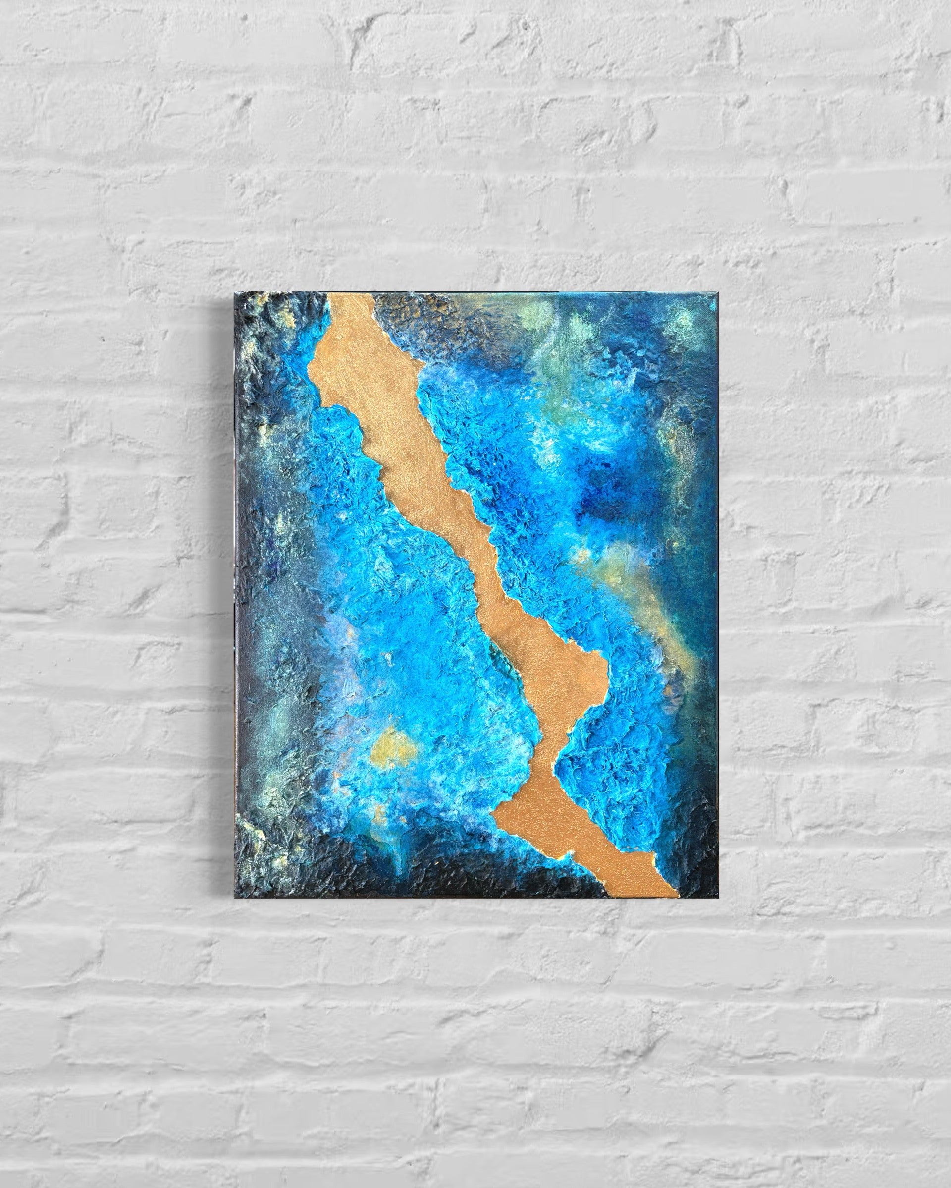 Abstract painting with blue and gold on a white brick wall
