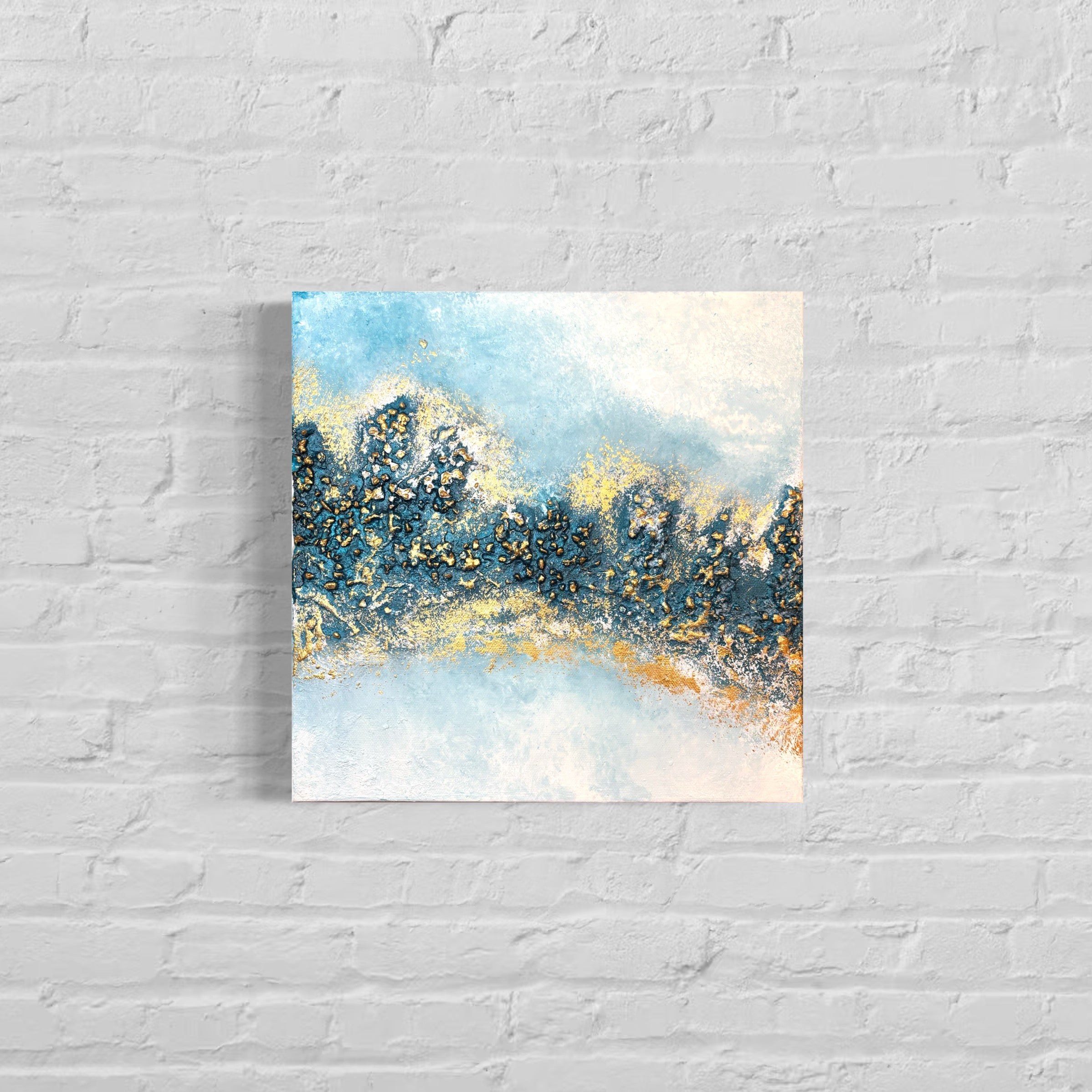 Abstract painting with blue and gold tones on a white brick wall