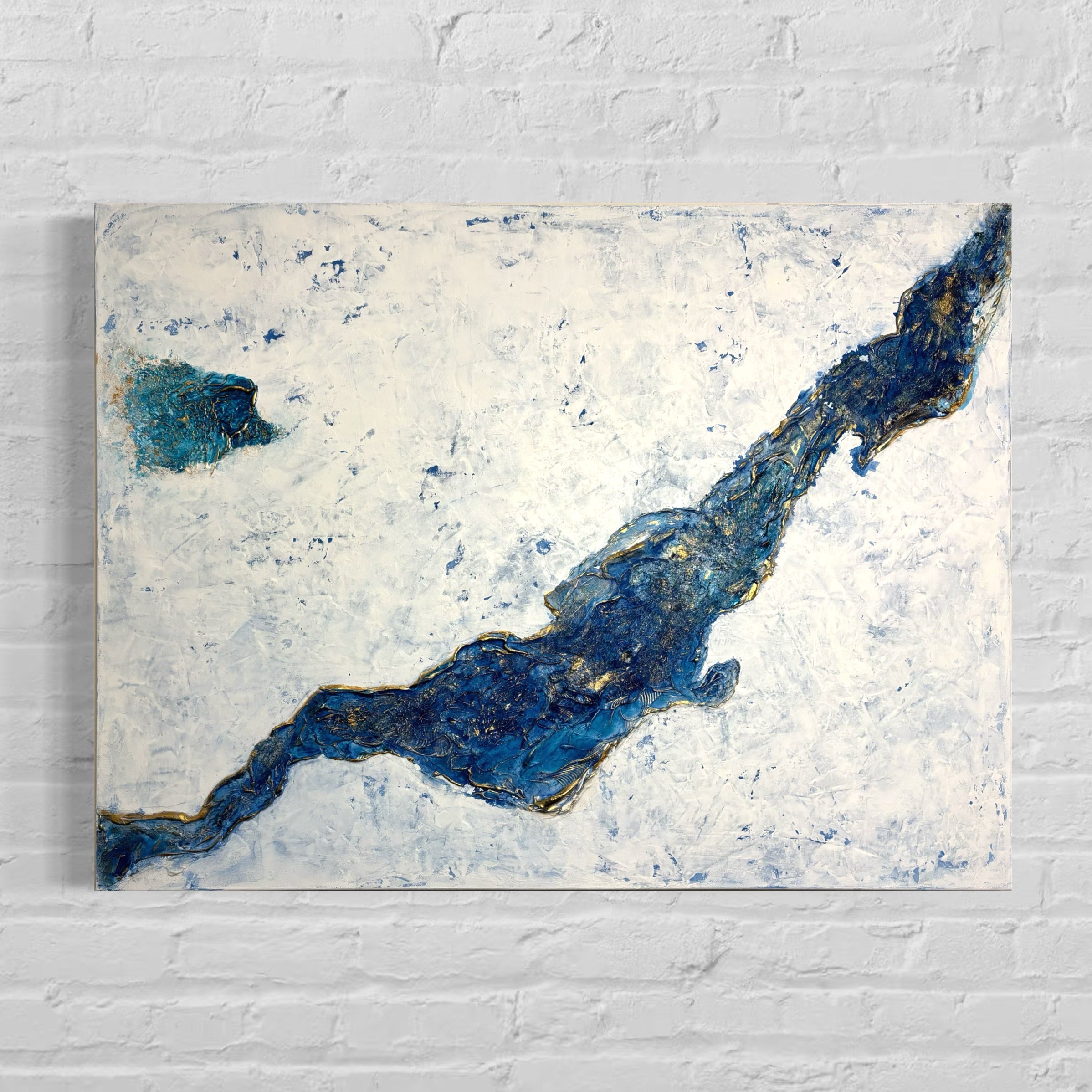 Abstract art piece with blue and gold accents on a white brick wall