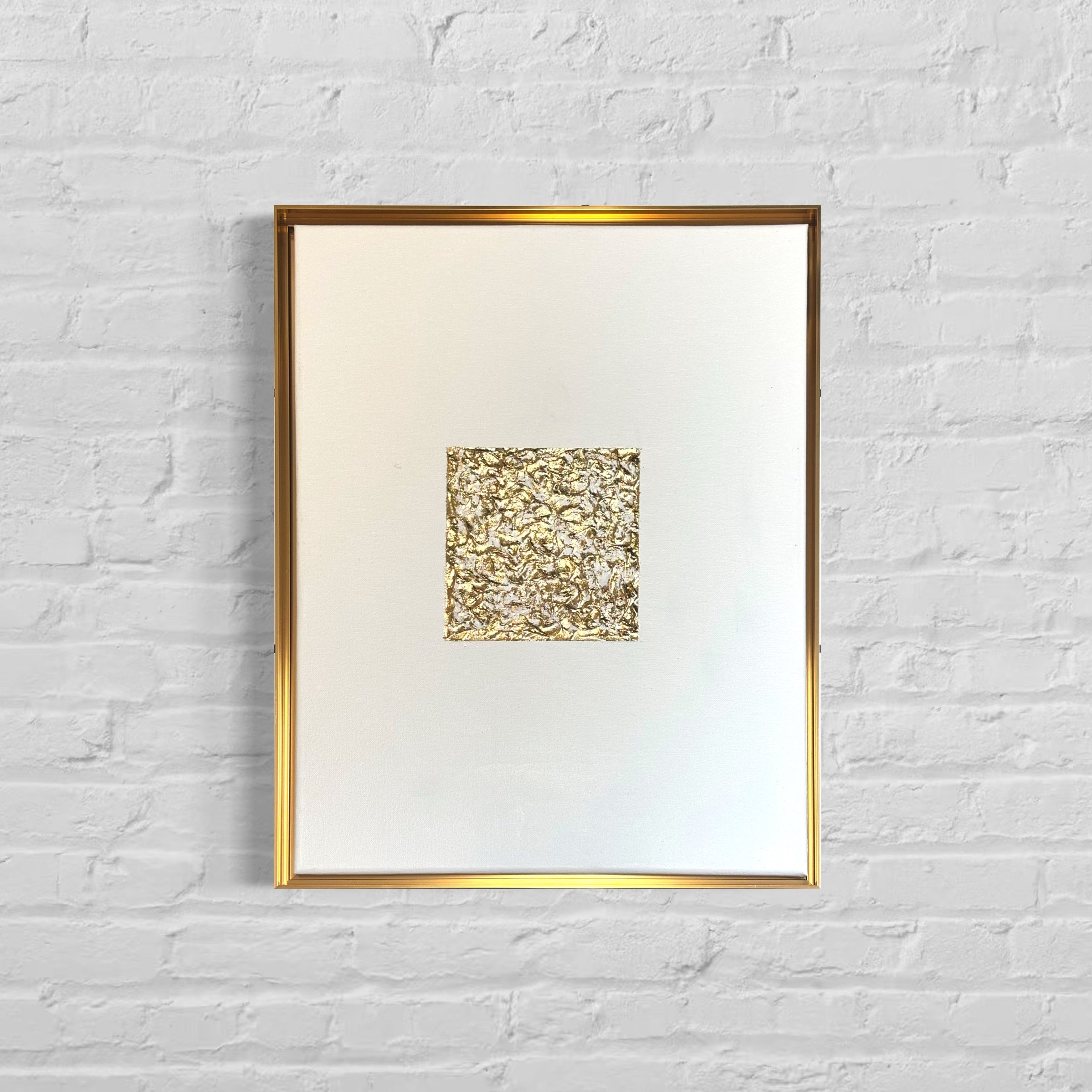 Framed artwork with a gold abstract design on a white background